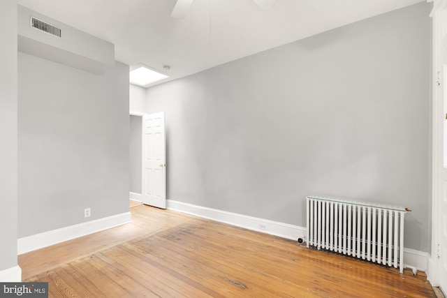 spare room with ceiling fan, wood-type flooring, and radiator heating unit