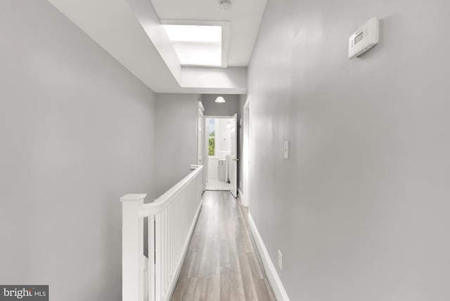 corridor with wood-type flooring and a skylight