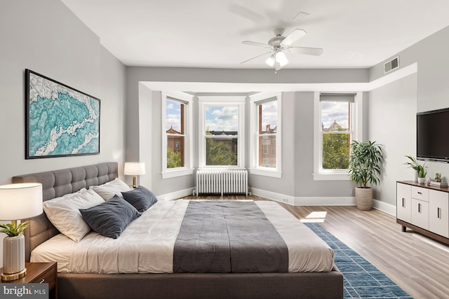 bedroom with radiator, ceiling fan, and light wood-type flooring