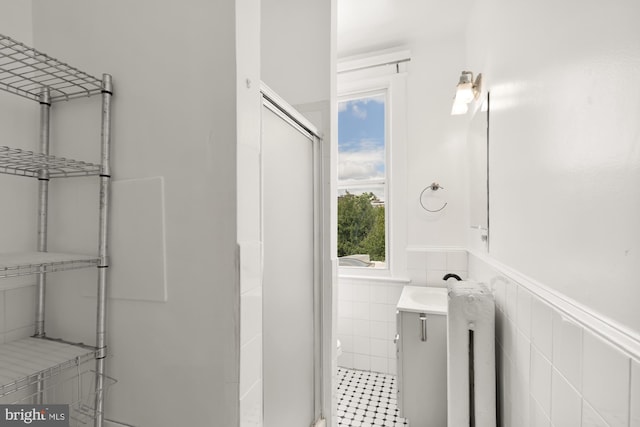 bathroom featuring toilet, walk in shower, vanity, and tile walls