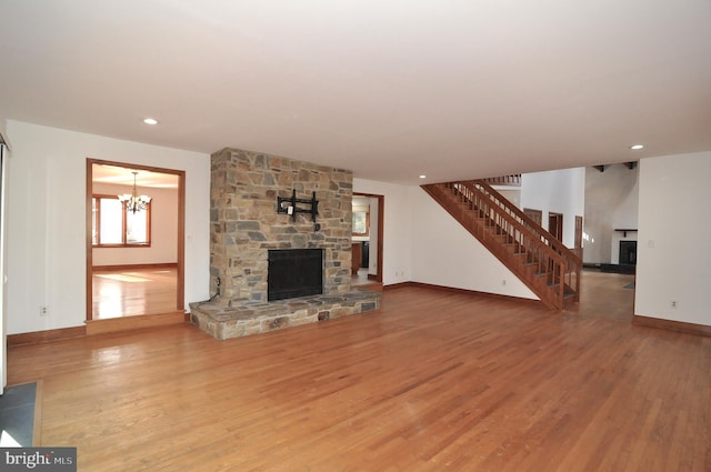 unfurnished living room featuring hardwood / wood-style floors, a fireplace, and a chandelier