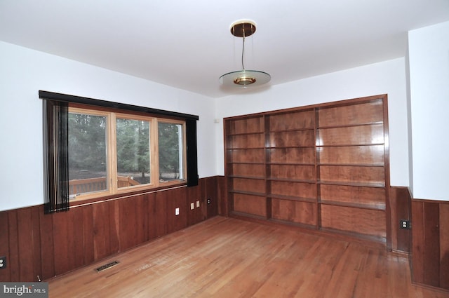 empty room featuring wooden walls and light hardwood / wood-style flooring