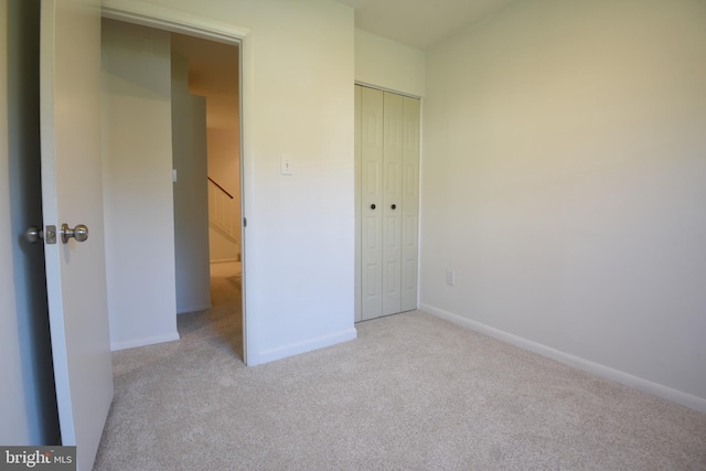 unfurnished bedroom with a closet and light carpet