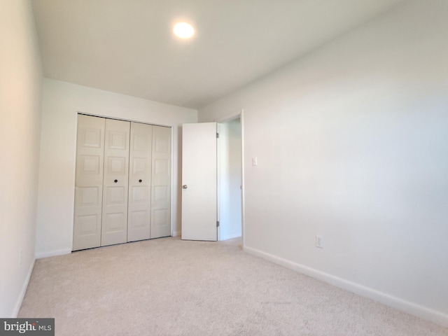 unfurnished bedroom featuring light colored carpet and a closet