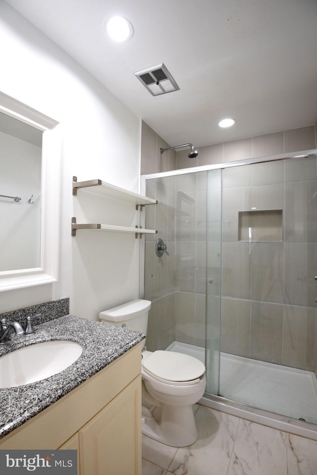 bathroom featuring vanity, a shower with shower door, and toilet