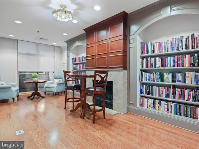 sitting room with a chandelier, built in shelves, light hardwood / wood-style floors, and a fireplace