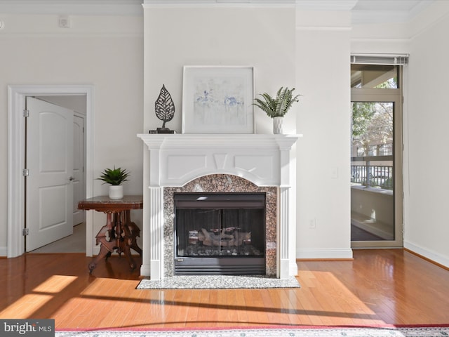 living area with baseboards, crown molding, wood finished floors, and a fireplace