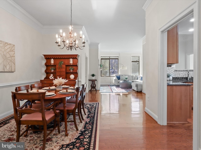 dining area featuring hardwood / wood-style floors, an inviting chandelier, ornamental molding, and sink