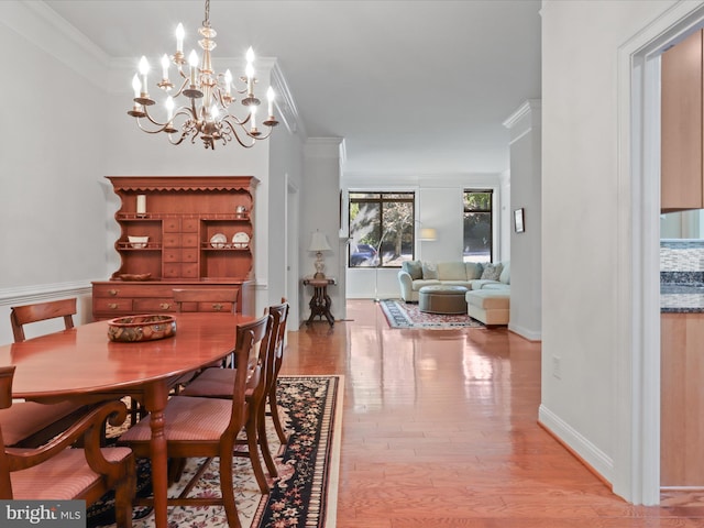 dining room featuring ornamental molding, a notable chandelier, and light wood-type flooring