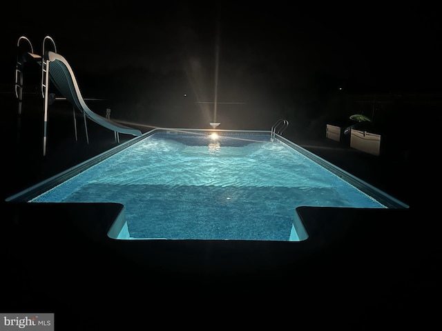 pool at night featuring a water slide