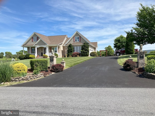 craftsman-style home with covered porch, a garage, and a front lawn