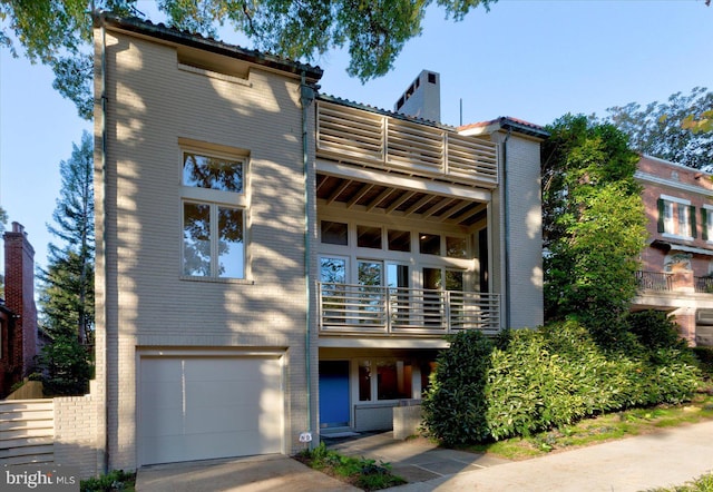 rear view of house featuring a balcony and a garage