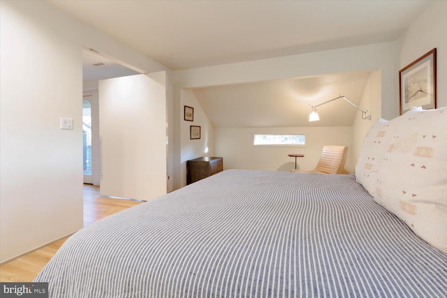 bedroom with light wood-type flooring and vaulted ceiling