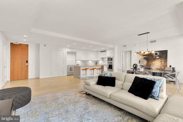 living room with a chandelier and light hardwood / wood-style flooring