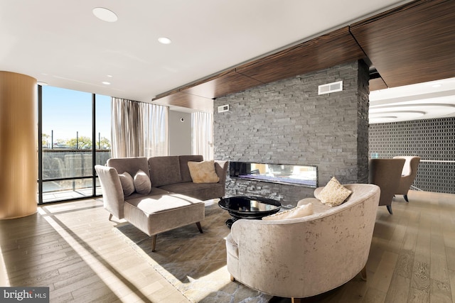 living room with light wood-type flooring, a fireplace, and floor to ceiling windows