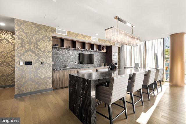 kitchen with a kitchen breakfast bar, an inviting chandelier, sink, light hardwood / wood-style floors, and a center island