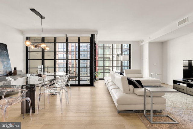 living room with expansive windows, light hardwood / wood-style flooring, and an inviting chandelier