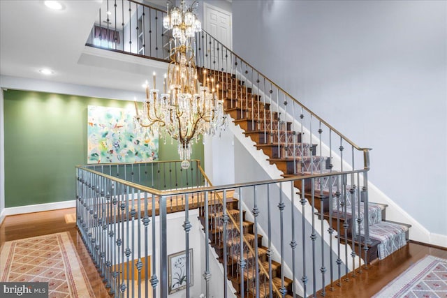 stairway featuring hardwood / wood-style flooring and an inviting chandelier