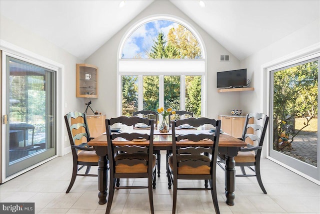 tiled dining room with a healthy amount of sunlight and lofted ceiling