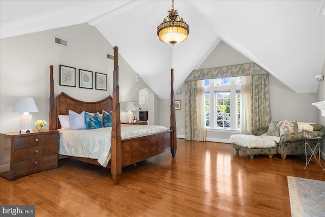 bedroom with vaulted ceiling with beams and hardwood / wood-style flooring