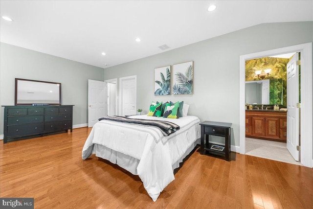 bedroom with sink, connected bathroom, light wood-type flooring, and vaulted ceiling