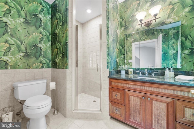 bathroom featuring an enclosed shower, toilet, tile walls, vanity, and tile patterned flooring