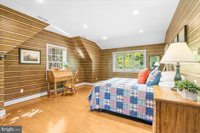 bedroom featuring lofted ceiling, wooden walls, and wood-type flooring