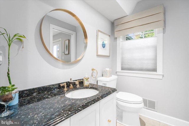 bathroom with toilet, vanity, and tile patterned floors