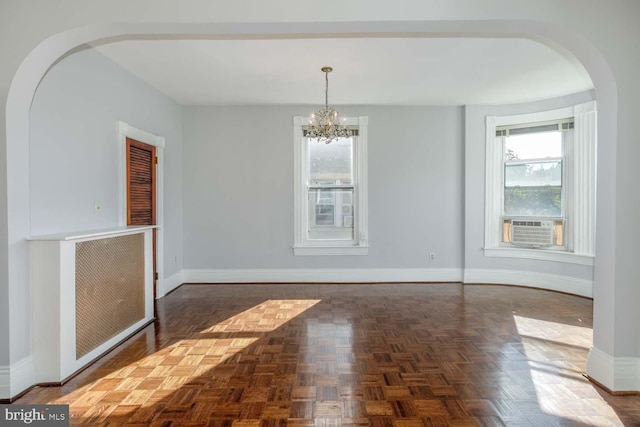 unfurnished dining area featuring cooling unit, dark parquet flooring, and a chandelier