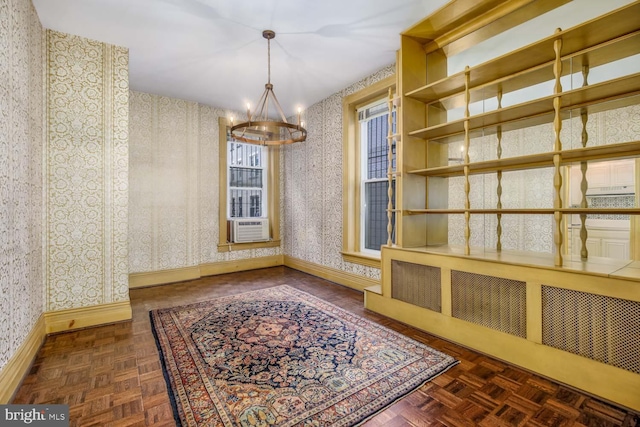 unfurnished room with radiator, dark parquet floors, an inviting chandelier, and cooling unit