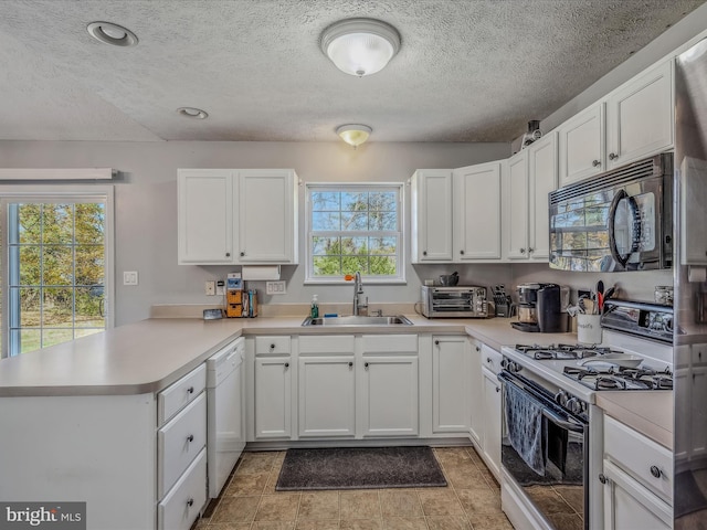 kitchen featuring a wealth of natural light, white appliances, sink, and kitchen peninsula