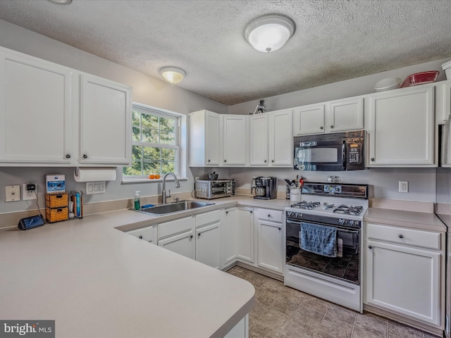 kitchen featuring white range with gas cooktop, sink, and white cabinets