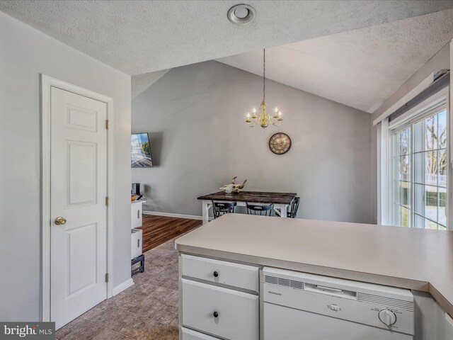 kitchen featuring white dishwasher, vaulted ceiling, kitchen peninsula, hanging light fixtures, and light wood-type flooring