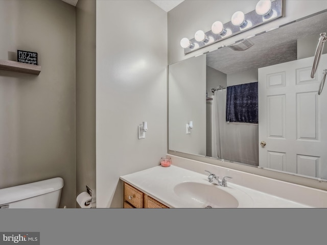 bathroom featuring vanity, a textured ceiling, and toilet