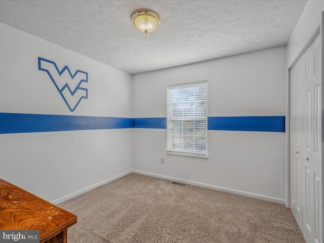 empty room featuring a textured ceiling and carpet flooring