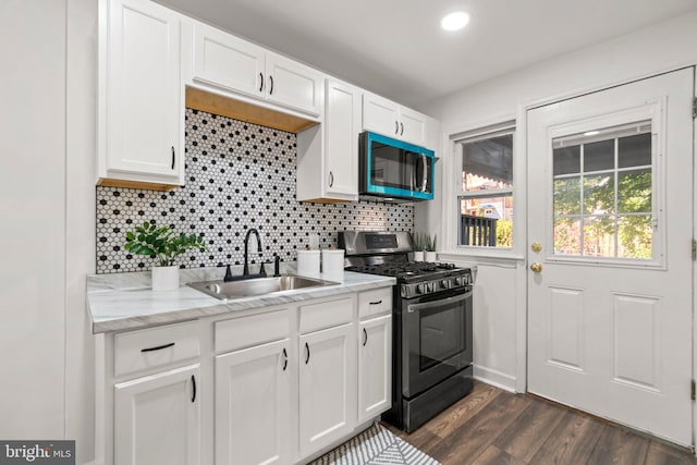 kitchen featuring dark hardwood / wood-style floors, black gas stove, sink, white cabinetry, and light stone counters