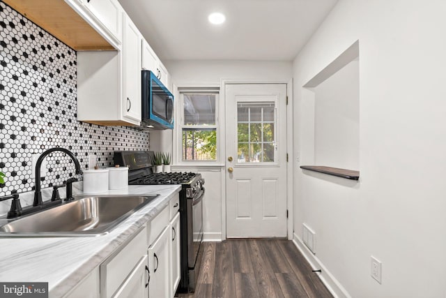 kitchen featuring white cabinets, backsplash, dark wood-type flooring, black range with gas cooktop, and sink