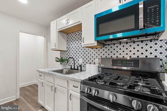 kitchen featuring decorative backsplash, white cabinets, wood-type flooring, black range with gas stovetop, and sink