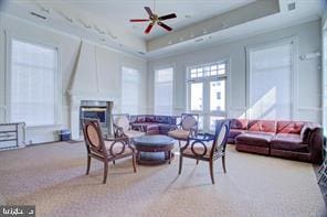 living room featuring carpet flooring, ceiling fan, and a raised ceiling