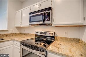 kitchen with light stone countertops, white cabinetry, and stainless steel appliances