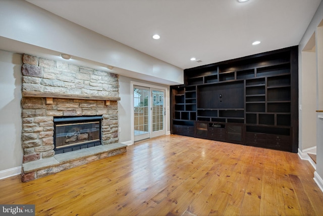 unfurnished living room with a stone fireplace and light wood-type flooring