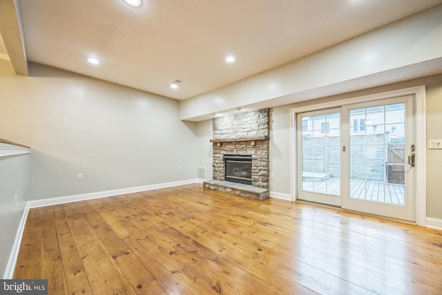 unfurnished living room with light hardwood / wood-style floors and a stone fireplace