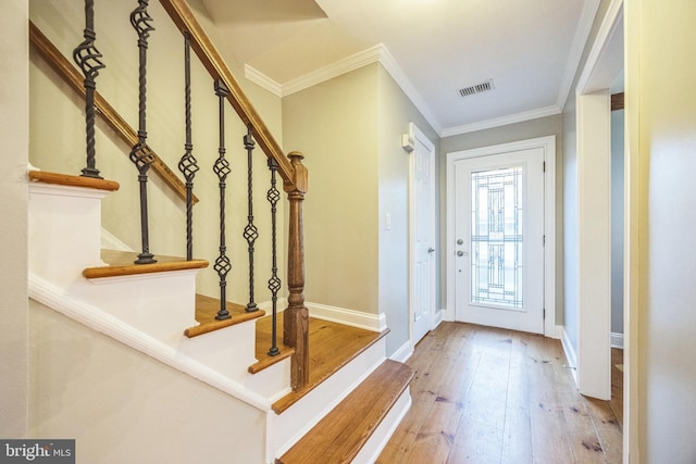 entrance foyer with ornamental molding and light hardwood / wood-style flooring