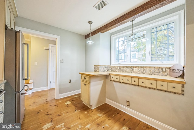 kitchen with stainless steel fridge, light wood-type flooring, and backsplash