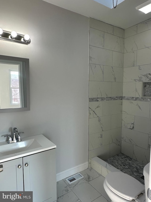 bathroom featuring toilet, vanity, and tiled shower