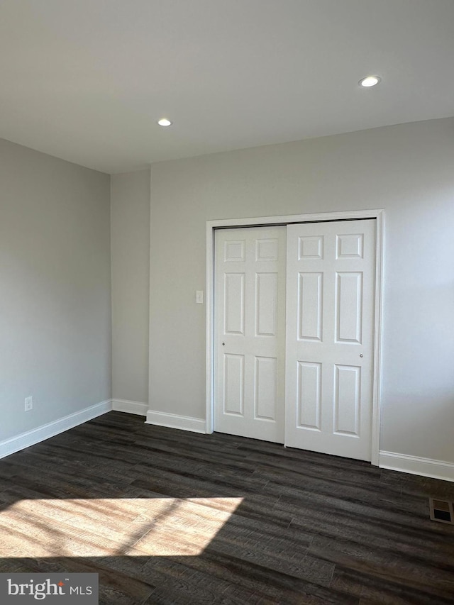 unfurnished bedroom with a closet and dark hardwood / wood-style flooring