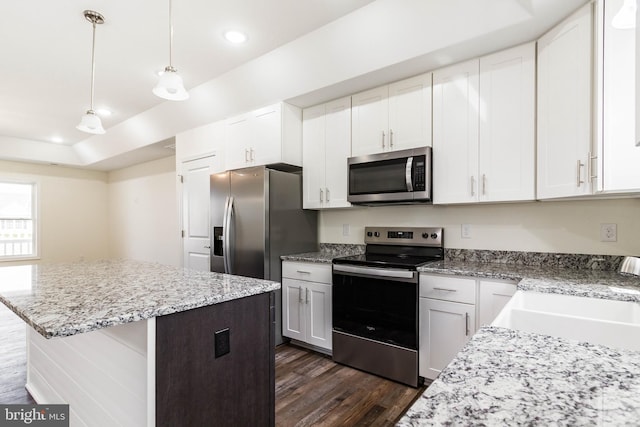 kitchen with white cabinetry, stainless steel appliances, a kitchen island, and hanging light fixtures