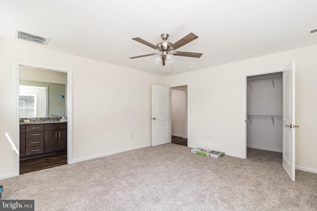 unfurnished bedroom featuring ceiling fan, sink, a closet, ensuite bath, and light colored carpet