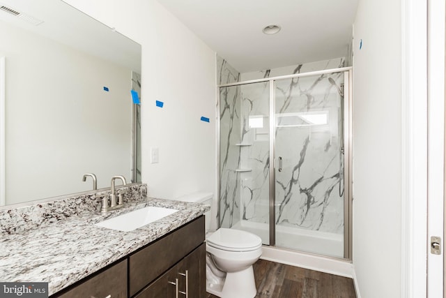 bathroom with vanity, a shower with shower door, hardwood / wood-style floors, and toilet