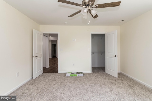 unfurnished bedroom with a closet, ceiling fan, carpet, and a walk in closet